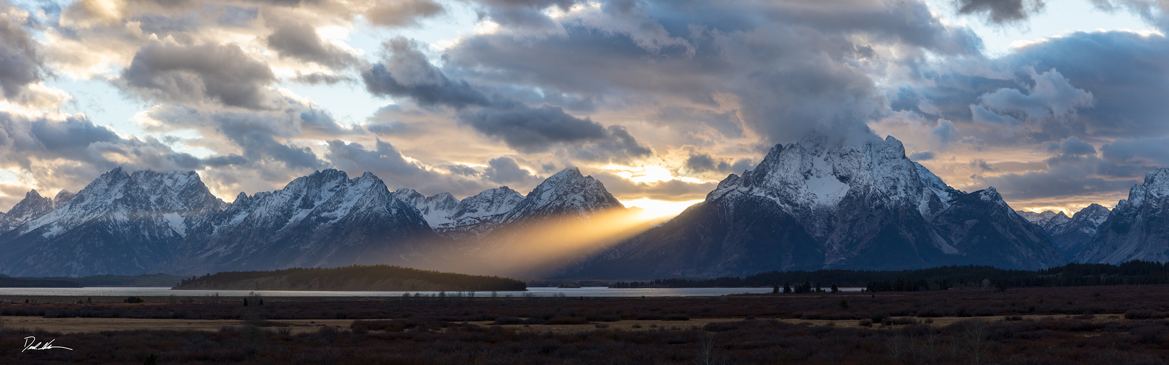 a sunbeam splits the Tetons mountains at sunset
