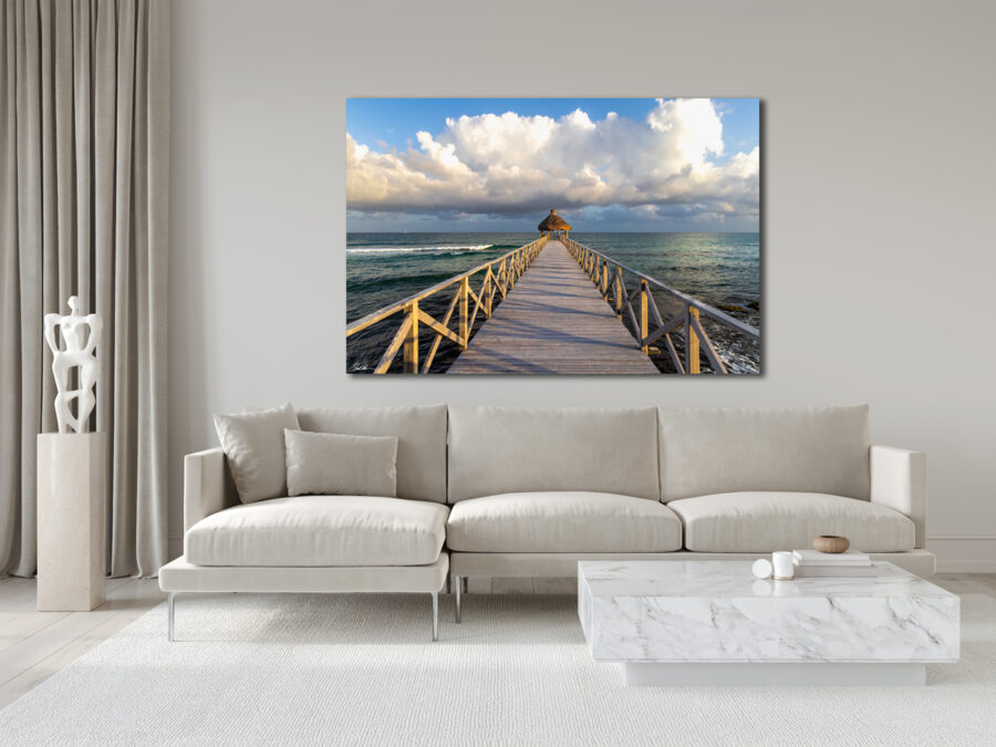 large unframed print of a boardwalk leading out into the Caribbean Sea at sunset displayed in the living room of a modern home