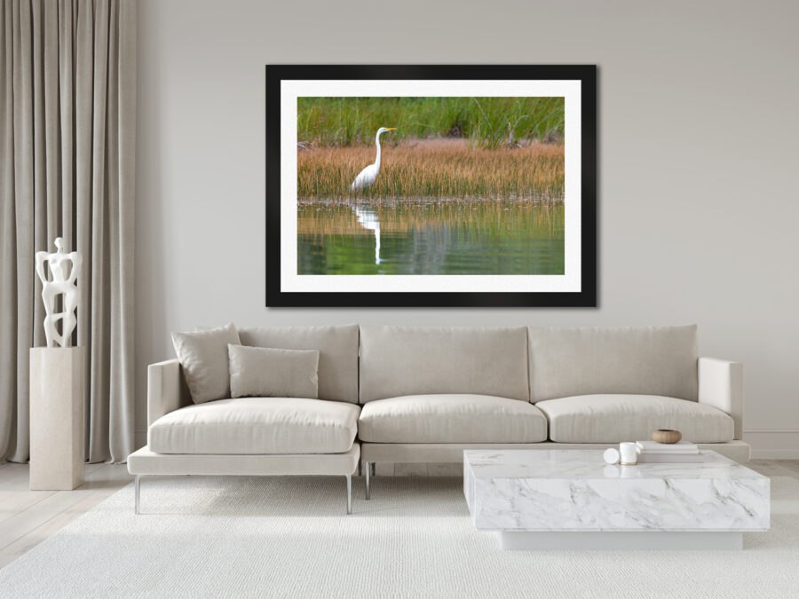 Large framed fine art print of an egret fishing on a lake displayed in the living room of a luxury home