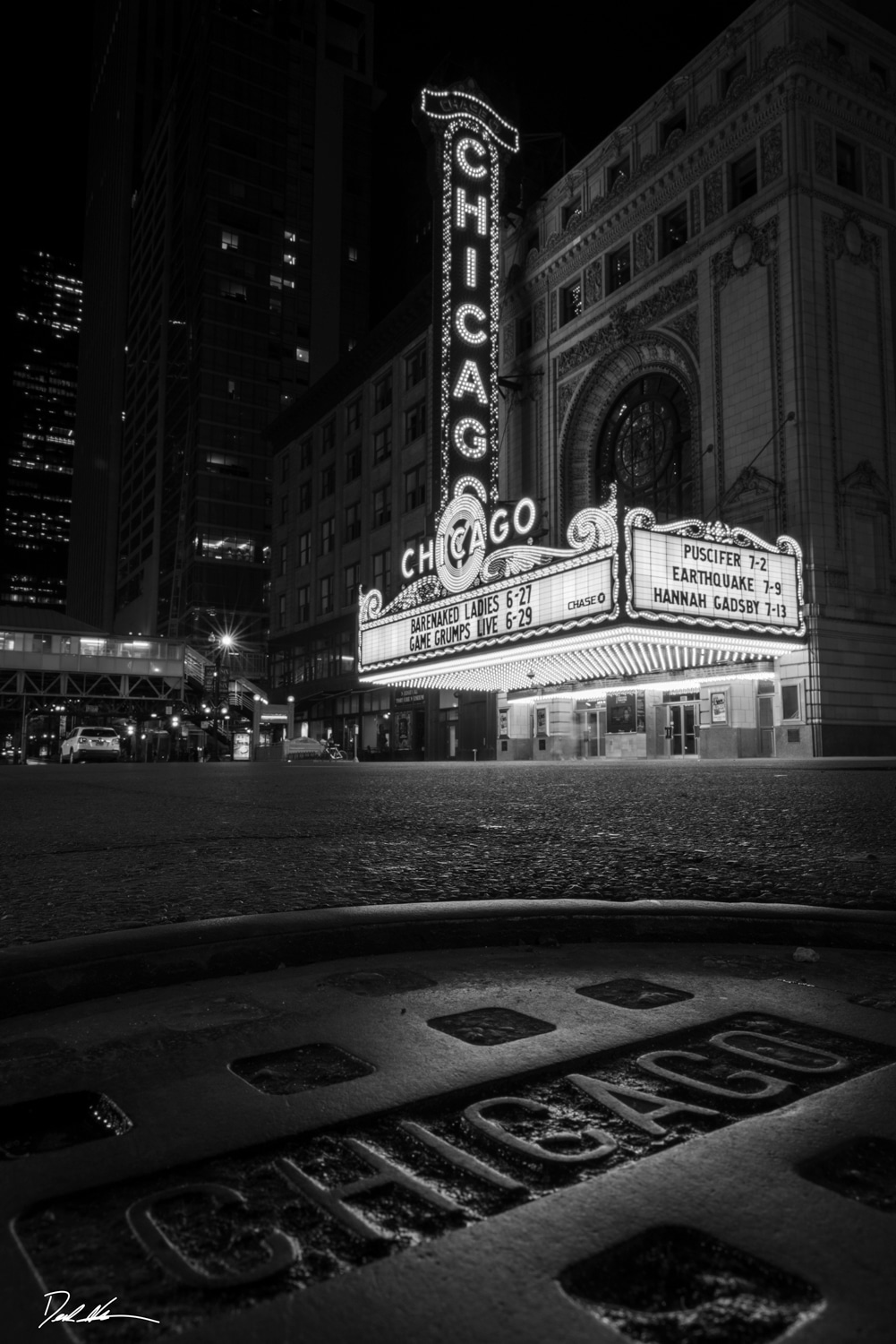 black and white image of a sewer cap in front of the Chicago Theatre