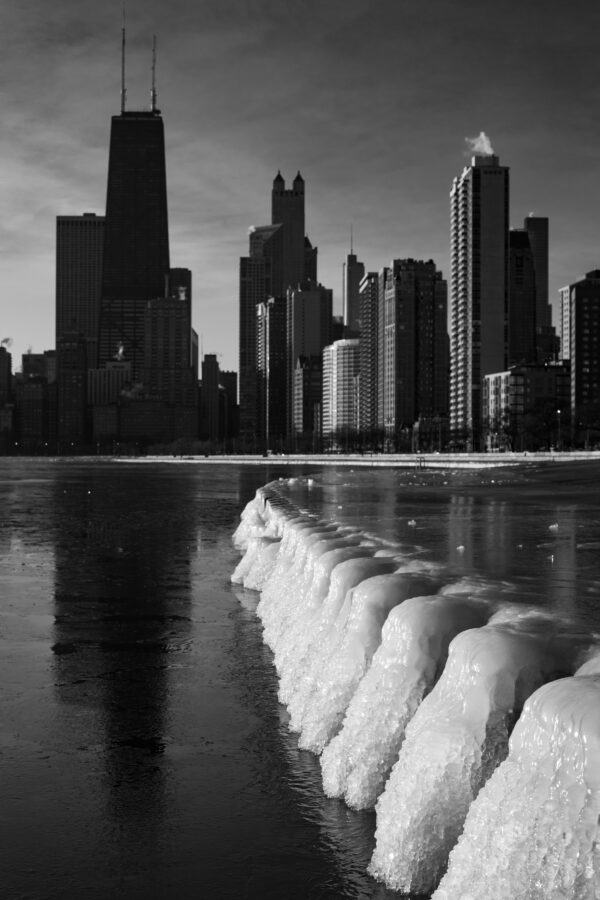 vertical black and white photo of Chicago with a wall of ice leading the eye into the scene 