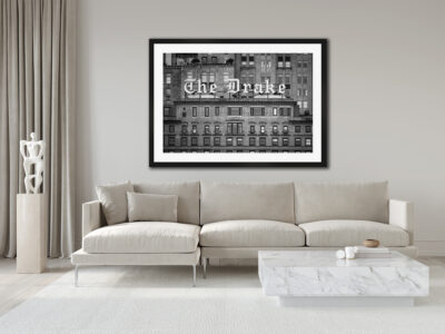 Large framed black and white image of the Drake Hotel in Chicago displayed above the couch of a clean white living room