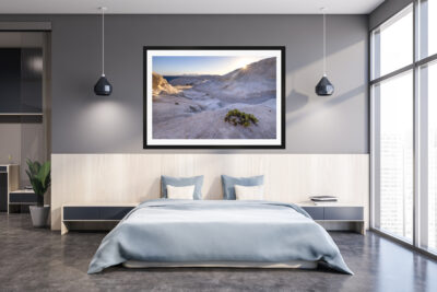 Large framed fine art print of Sarakiniko beach in Greece displayed above a bed in a luxury home