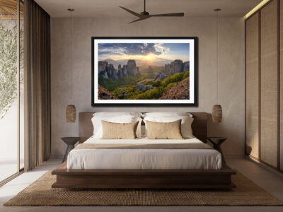 Large framed fine art print of Meteora Greece displayed above a bed in a modern luxury bedroom