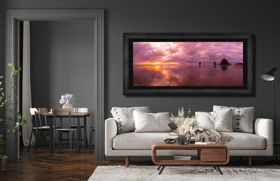 Large framed fine art print of Canon Beach in Oregon displayed above a couch in a luxury home