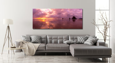 Large unframed panoramic fine art print of Canon Beach in Oregon displayed above the couch of a modern home
