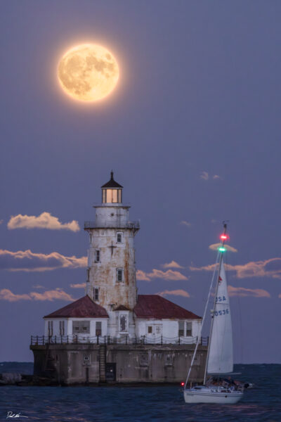 image of a super moon rising over Chicago's Navy Pier lighthouse with a sailboat in the foreground