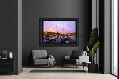 Large framed fine art print of sailboats under a rainbow in Friday Harbor displayed in the living room of a modern home