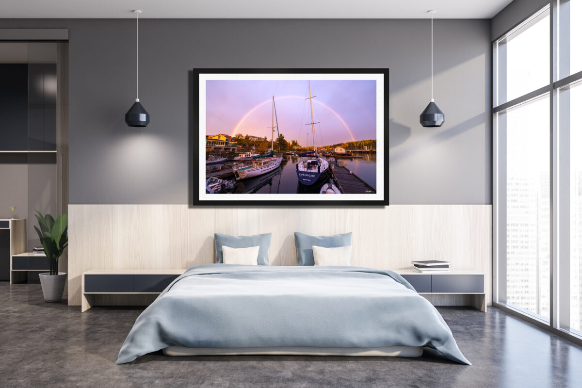 Large framed print of sailboats under a rainbow in Friday Harbor displayed above a bed in a modern apartment