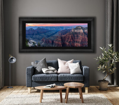 large framed panoramic print of the Grand Canyon during sunset displayed above a couch in a modern home