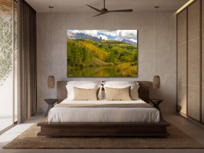 large unframed fine art print of a mountain scene during fall on a lake displayed in the bedroom of a luxury hotel
