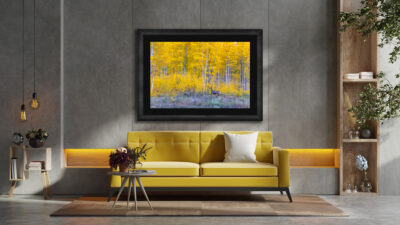 Large framed print of a deer running in front of aspen trees displayed in the living room of a modern home