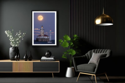 large fine art framed print of a super moon rising behind Chicago's Navy Pier lighthouse with a sailboat crossing in front displayed in the living room of a luxury home