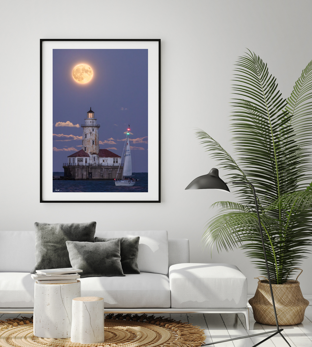 large fine art framed print of a super moon rising behind Chicago's Navy Pier lighthouse with a sailboat crossing in front displayed in the living room of a modern home