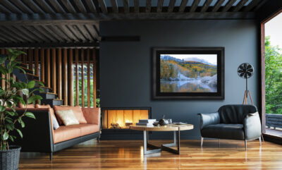 large dark framed fine art print of a mountain scene with fall colors and show displayed in the living room of a modern luxury home