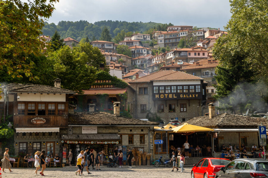 image of the town of Metsovo Greece with people walking through the town square and the buildings rising up behind them