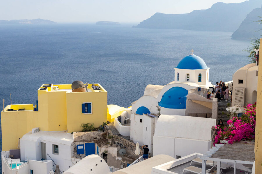 image of the blue domes of Santorini with colorful flowers and buildings next to them looking over the sea