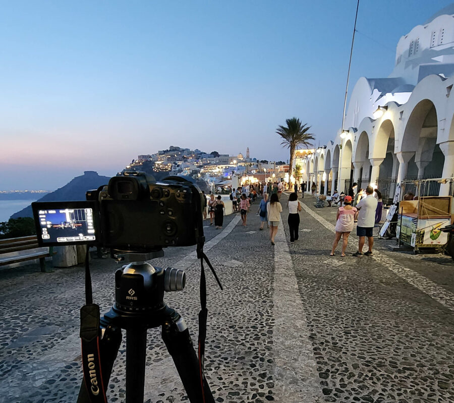 image of a camera on the walkway in Fira a neighborhood in Santorini Greece at night looking over the town