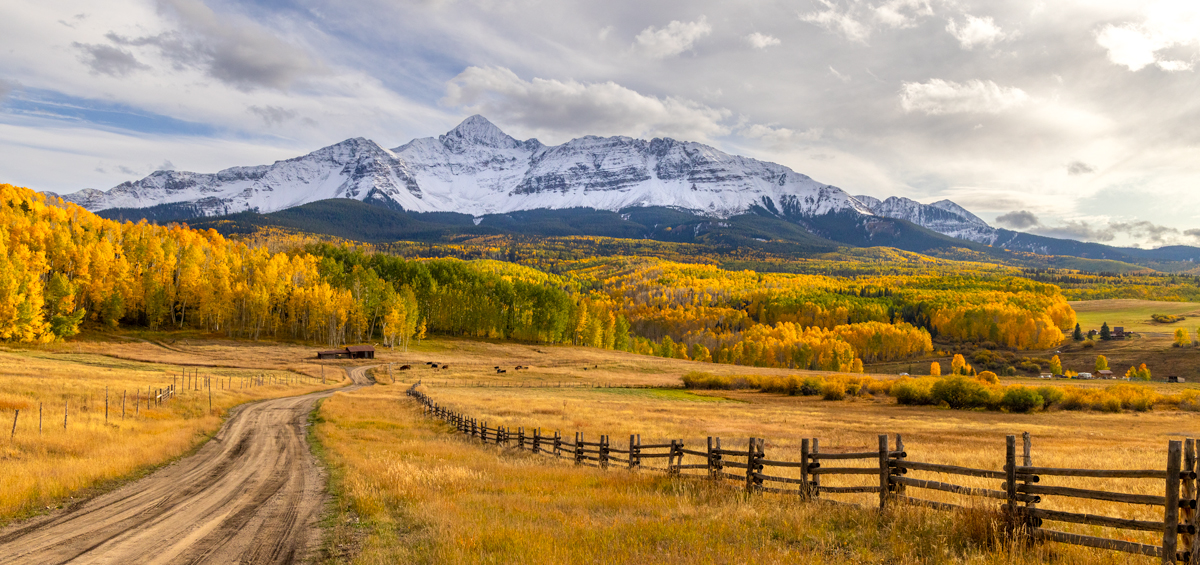 panoramic image of Wilson Peak in Telluride Colorado with golden fall colors and snow-capped peaks