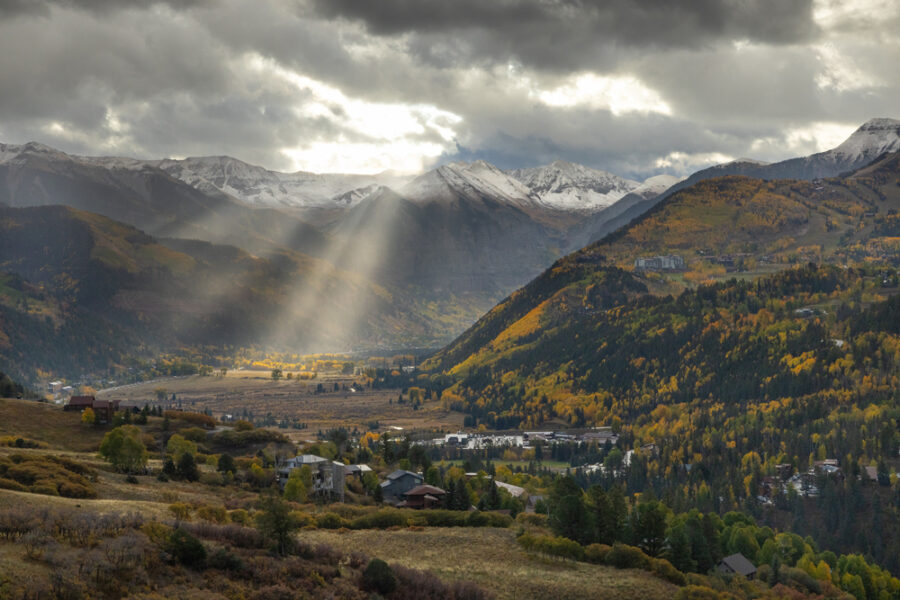 elevated image of Telluride Colorado with sunbeams cutting through the clouds shining over the town