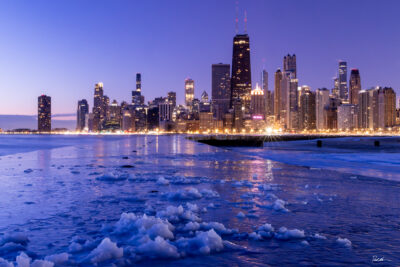 Beautiful image of Chicago taken during blue hour with ice in the foreground.