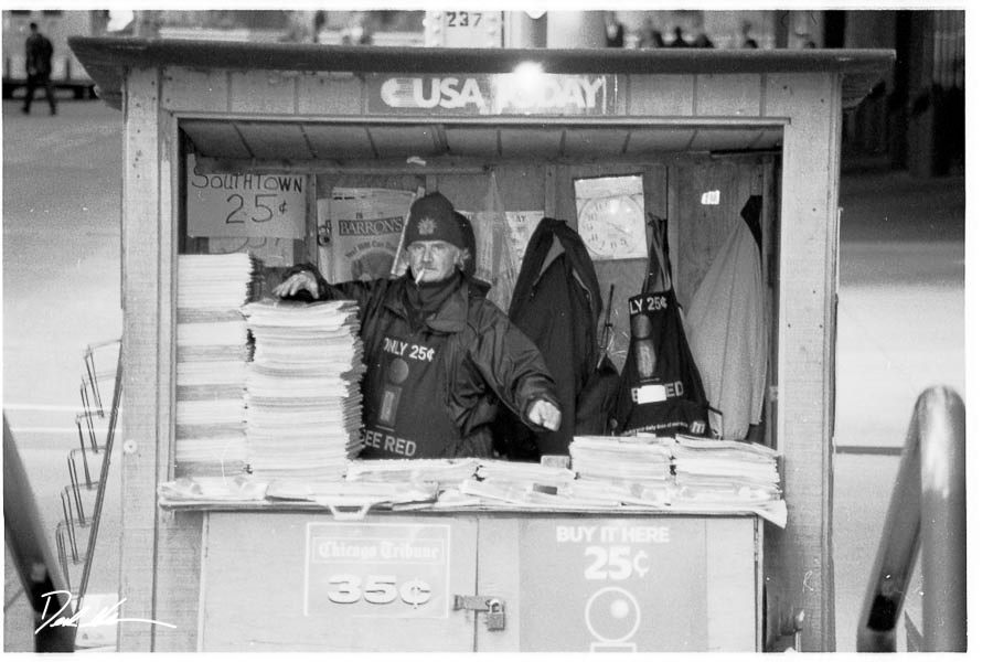 Image of a Chicago newspaper stand guy in black and white from a selection of Chicago photography prints