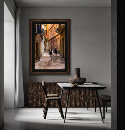 Large framed fine art print of two Spanish women walking down the narrow streets of Barcelona displayed in a dining room of a modern home