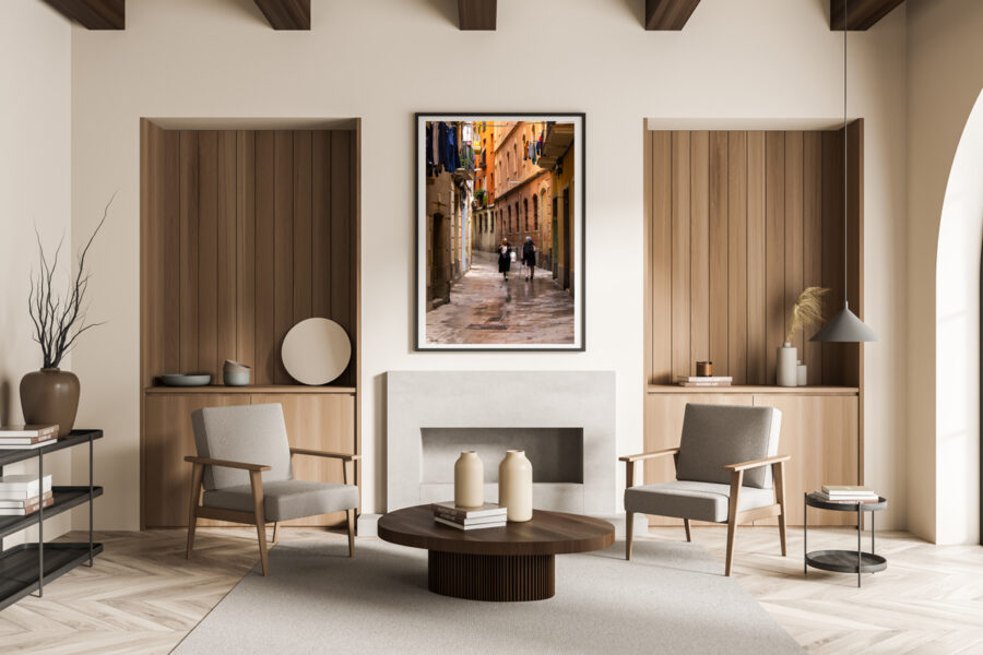 Large framed fine art print of two women walking down a narrow street in Barcelona displayed in the living room of a modern home