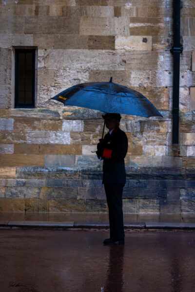 Large fine art image of a British woman holding an umbrella in the rain outside Windsor Castle, England