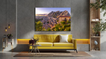 Large unframed fine art print of Pietrapertosa Italy displayed above a couch in a living room of a modern city apartment