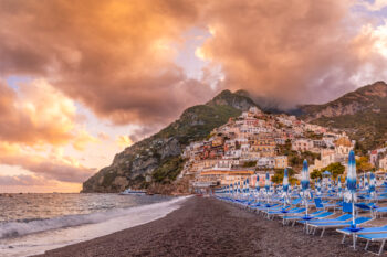 beautiful sunset photo of Positano Italy on the Amalfi Coast with iconic blue beach chairs