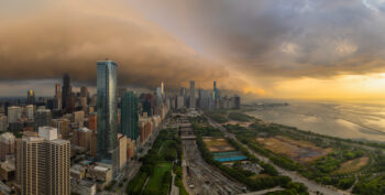 Large panoramic photo of the city of chicago with a storm cloud over the city at sunrise