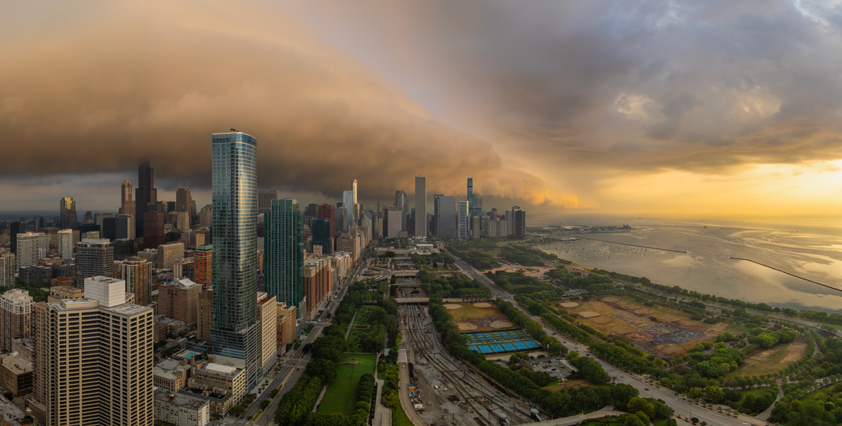 Large panoramic photo of the city of chicago with a storm cloud over the city at sunrise