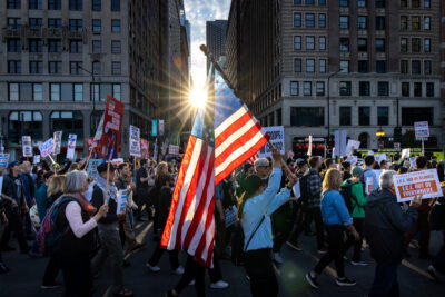 Photograph of protesters in Chicago marching with the American Flag while holding up signs