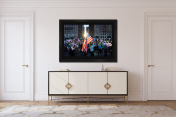 Large framed fine art print of protesters in Chicago carrying the american flag displayed in the hallway of a modern home