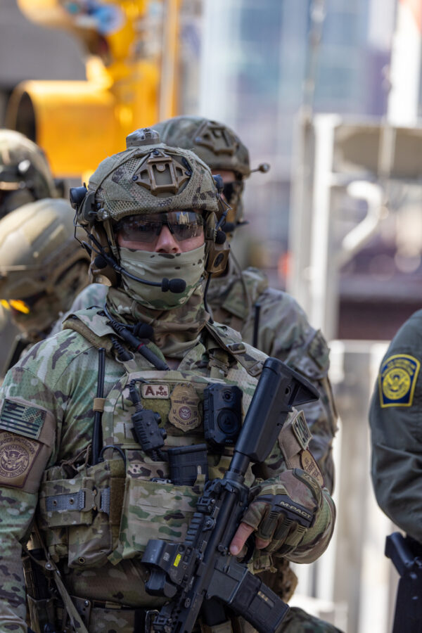 ICE agent in full military gear with high powered weapon