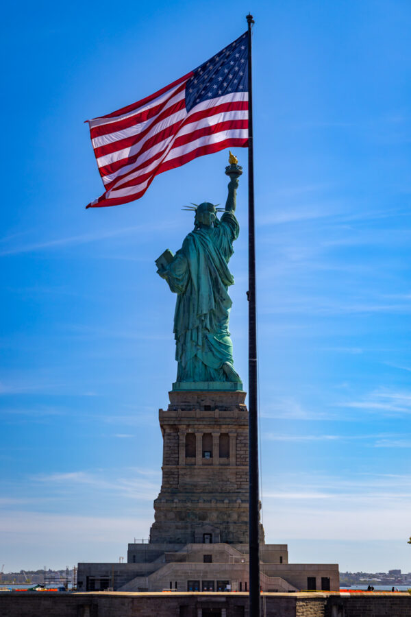 Image of the Statue of Liberty with an american flag abover her