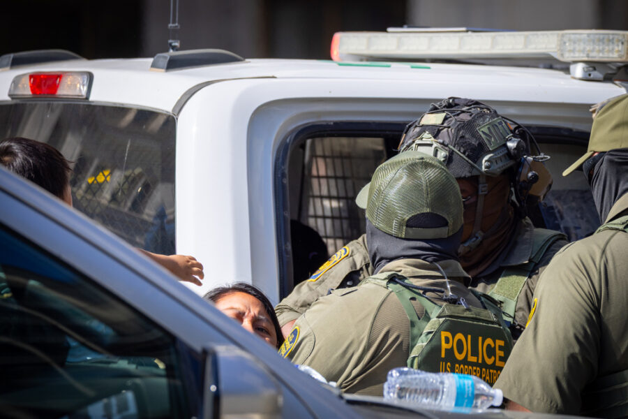 A hispanic woman being pulled apart from her child while being detained by ICE