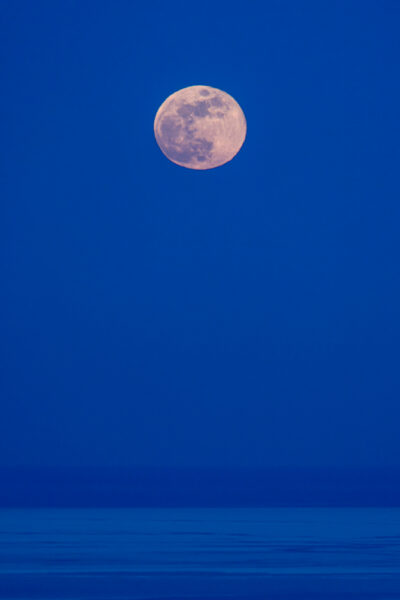 fine art photograph of the moon raising over lake michigan in the winter