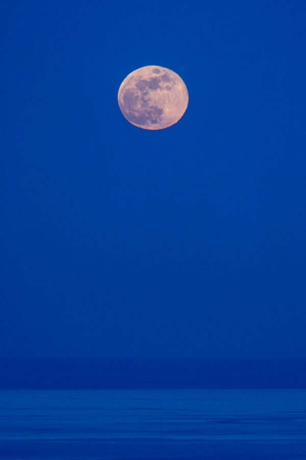 fine art photograph of the moon raising over lake michigan in the winter