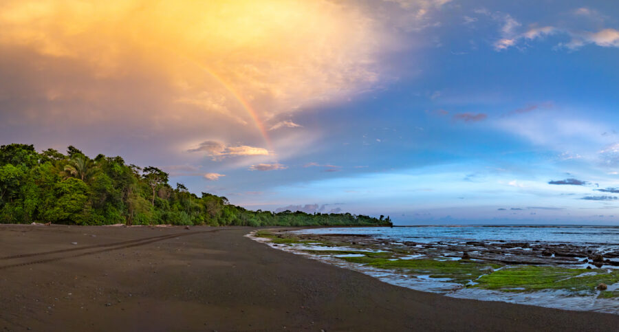 photograph of corcovado nationl park in Costa Rica at sunset with a rainbow on the beach