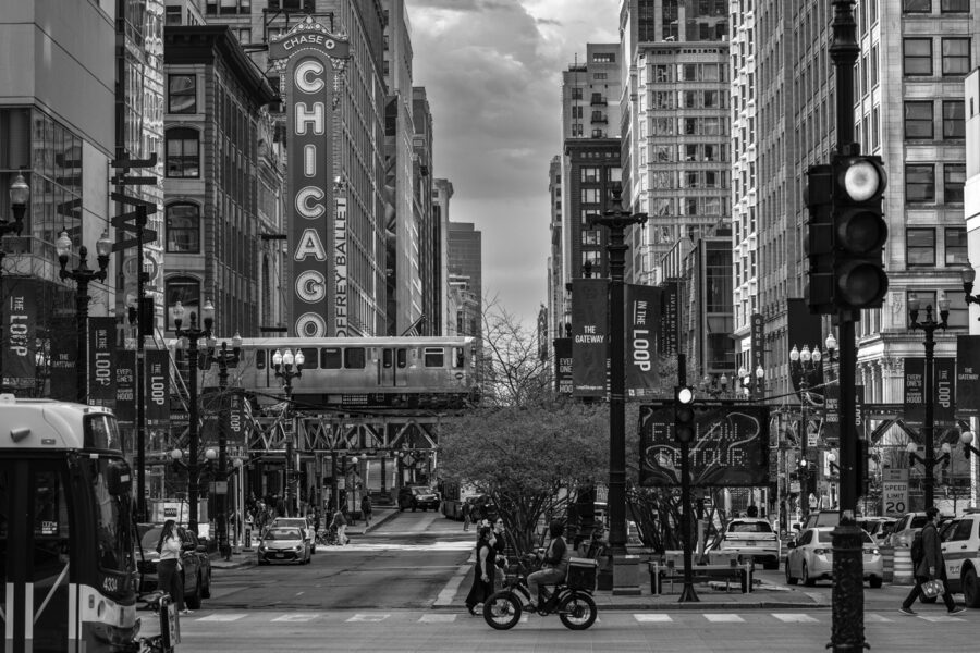 black and white photo of state street in Chicago with a train going by